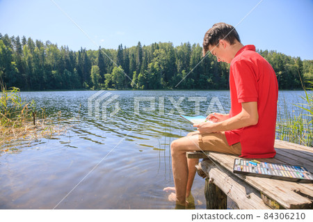 Teen boy sketching summer landscape with pastel sticks 84306210