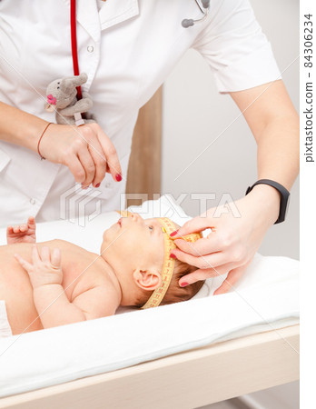 Infant medical exam - doctor checking head size with a measurement tape 84306234