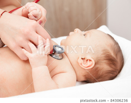 Infant medical exam - doctor checking heart beat and lungs with stethoscope 84306236