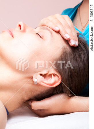 Woman receiving osteopathic treatment of her head Woman receiving osteopathic treatment of her head 84306245
