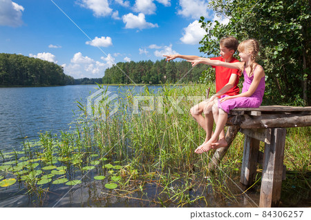 Children birdwatching at a summer lake 84306257