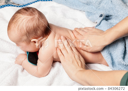 Little baby receiving chiropractic treatment of her back at home 84306272