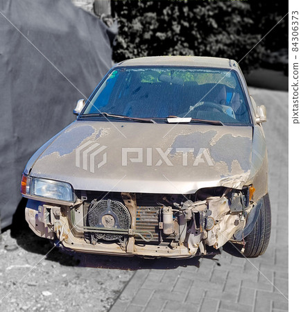 A car that has received the destruction of the front part of the body and the engine as  result of a road traffic accident - head-on collision with another car 84306373