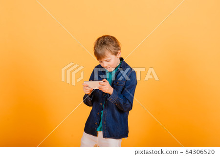 The little boy phones on the yellow background 84306520