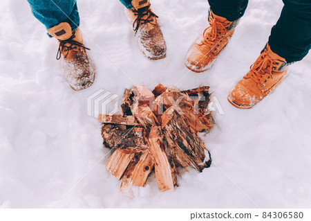 Two people stand in the snow near campfire. Winter theme Two people stand in the snow near campfire. Winter theme 84306580