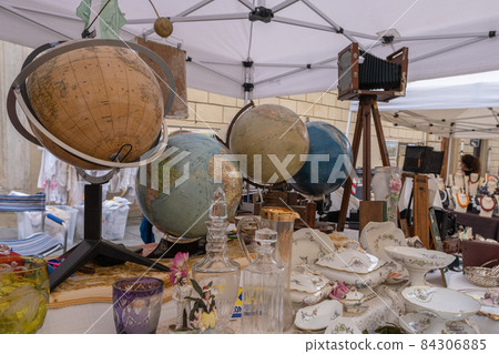 Old globes and porcelain on stand of antiques market in Arezzo Italy 84306885