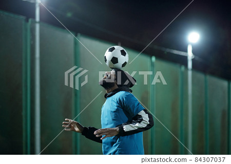Young professional soccer player with ball on his forehead Young professional soccer player with ball on his forehead 84307037