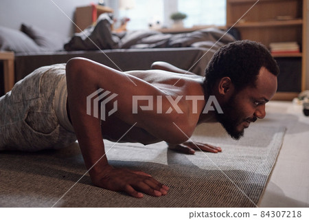 Young active man doing press-ups on the floor of bedroom Young active man doing press-ups on the floor of bedroom 84307218