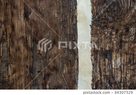 A thin strip of coarse cloth on a textured wooden surface A thin strip of coarse cloth on a textured wooden surface 84307329