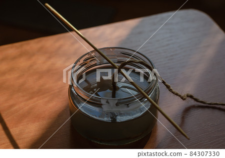 A homemade candle. The thread of the wick is filled with hot liq 84307330