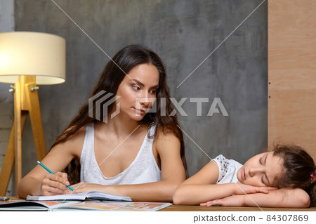 Portrait of a mother helping her small sweet and cute daughter to make her homework indoors. Happy family. 84307869