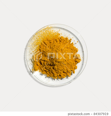 Closeup cosmetic chemical ingredient on white laboratory table. Organic Curcuma Powder in Chemical Watch Glass. Top View Closeup cosmetic chemical ingredient on white laboratory table. Organic Curcuma Powder in Chemical Watch Glass. Top View 84307919