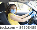 Young woman in a mask sitting in a car 84308489