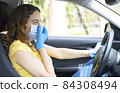 Young woman in a mask sitting in a car 84308494
