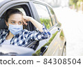 Young woman in a mask sitting in a car 84308504