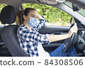 Young woman in a mask sitting in a car 84308506