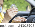 Young woman using hand sanitizer in a car 84308508