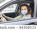 Young woman in a mask sitting in a car 84308515