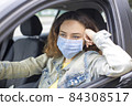 Young woman in a mask sitting in a car 84308517