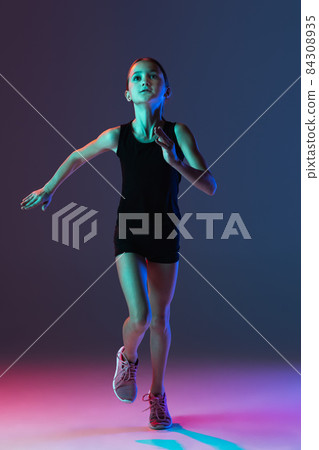 Front view portrait of teen girl, professional athlete running, training isolated over gradient background in neon 84308935