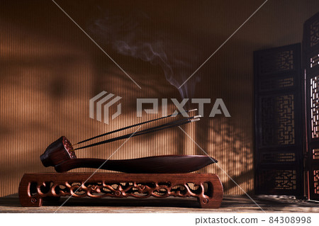 Smoke from burning incense sticks standing on lotus incense holder Smoke from burning incense sticks standing on lotus incense holder 84308998