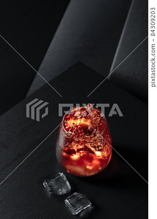 Ice cubes fall into a glass of whiskey. 84309203