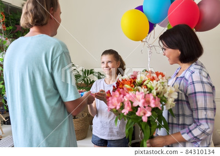 Parents congratulating daughter child with happy birthday, gift flowers balloons Parents congratulating daughter child with happy birthday, gift flowers balloons 84310134