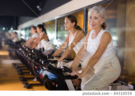 Mature woman taking cycling class at gym 84310559