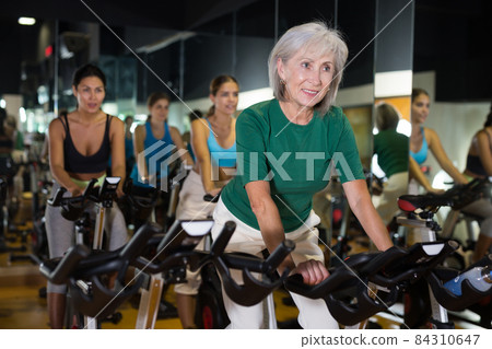 Mature woman taking cycling class at gym 84310647