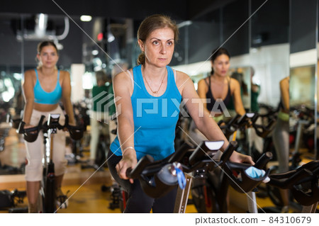 Woman riding stationary bike at fitness center Woman riding stationary bike at fitness center 84310679