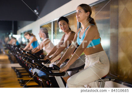 Woman taking indoor cycling class at gym 84310685