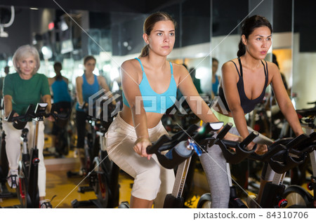 Women training on stationary bikes at gym 84310706