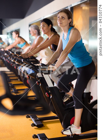 Woman riding stationary bike at fitness center 84310774