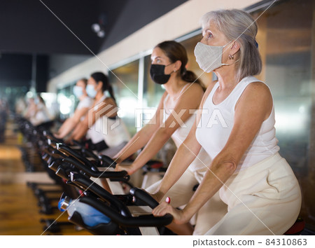 Mature woman in mask taking cycling class 84310863