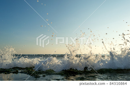 Sea waves breaking on a stony shore, forming sprays and splashes 84310864