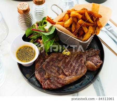 Veal entrecote with fried potatoes, fresh greens and caper sauce Veal entrecote with fried potatoes, fresh greens and caper sauce 84311061