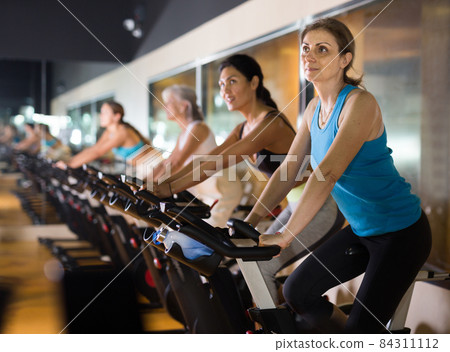 Woman riding stationary bike at fitness center 84311112