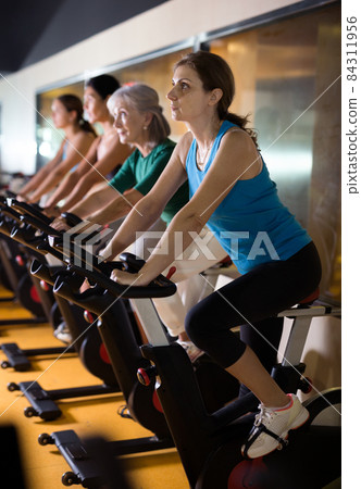 Woman riding stationary bike at fitness center 84311956