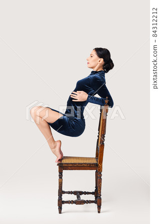 Pretty woman on the chair on tiptoe 84312212
