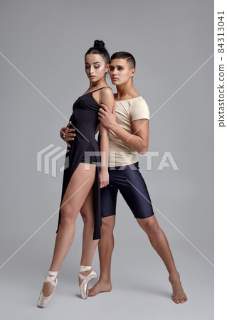 Two athletic modern ballet dancers are posing against a gray studio background. Two athletic modern ballet dancers are posing against a gray studio background. 84313041