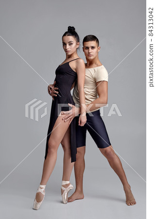 Two athletic modern ballet dancers are posing against a gray studio background. Two athletic modern ballet dancers are posing against a gray studio background. 84313042