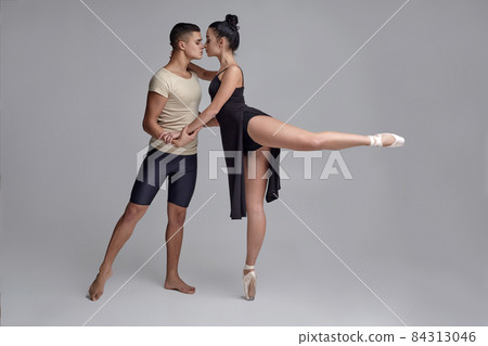 Two athletic modern ballet dancers are posing against a gray studio background. Two athletic modern ballet dancers are posing against a gray studio background. 84313046
