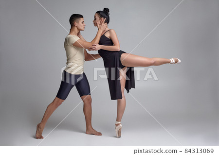 Two athletic modern ballet dancers are posing against a gray studio background. Two athletic modern ballet dancers are posing against a gray studio background. 84313069