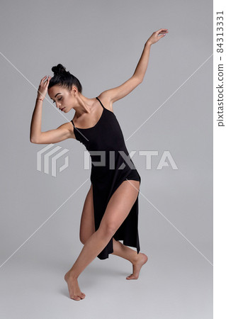 Dancing ballerina in a black dress. Contemporary graceful performance on a gray background. Dancing ballerina in a black dress. Contemporary graceful performance on a gray background. 84313331