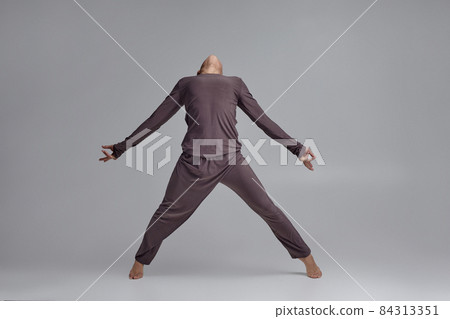 Photo of an athletic man ballet dancer dressed in a gray tracksuit, making a dance element against a gray background in studio. Photo of an athletic man ballet dancer dressed in a gray tracksuit, making a dance element against a gray background in studio. 84313351