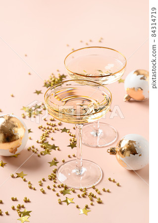 New Year champagne and Christmas gold baubles on white background. New Year champagne and Christmas gold baubles on white background. 84314719