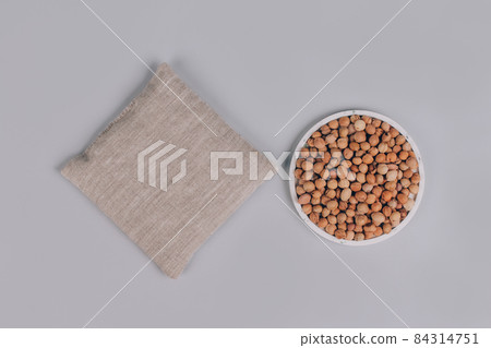 Top view on cherry stone pillow, cherry pit filled pillow with cherry stones around on gray background. Natural heat or cool pack. Alternative medicine and therapy, pit sack for spa massage. Mockup Top view on cherry stone pillow, cherry pit filled pillow with cherry stones around on gray background. Natural heat or cool pack. Alternative medicine and therapy, pit sack for spa massage. Mockup 84314751