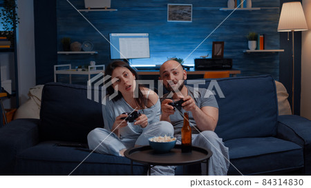 Focused determined couple playing video game late night 84314830