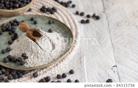 Plate and wooden scoop of black chickpea flour and beans closeup Plate and wooden scoop of black chickpea flour and beans closeup 84315736