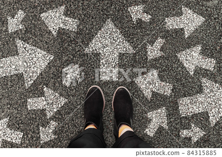 Person standing on road with arrow markings pointing in different directions, decision making concept Person standing on road with arrow markings pointing in different directions, decision making concept 84315885